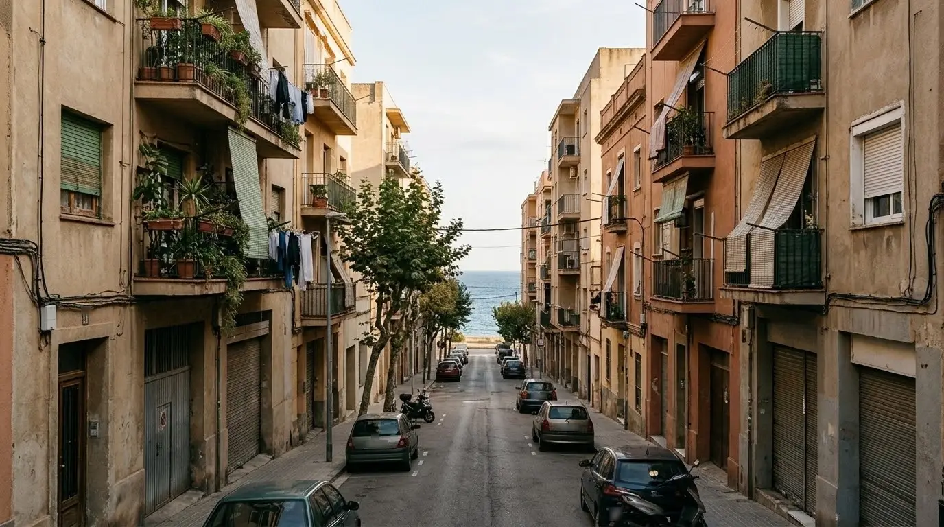Calle de Badalona con bloques de pisos de seis alturas, balcones con plantas y el mar al fondo